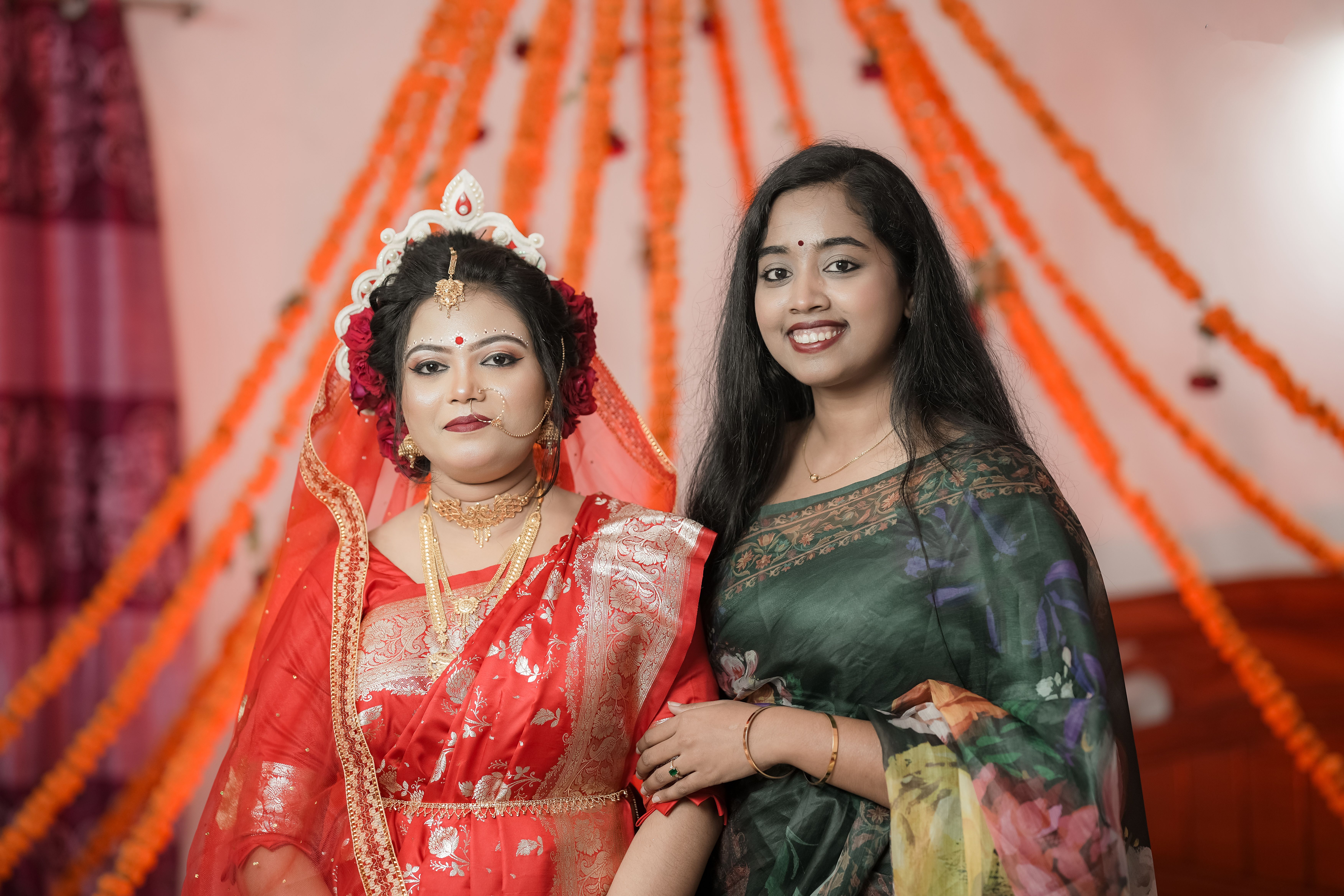 Bride and friend in vibrant attire at a traditional South Asian wedding celebration.