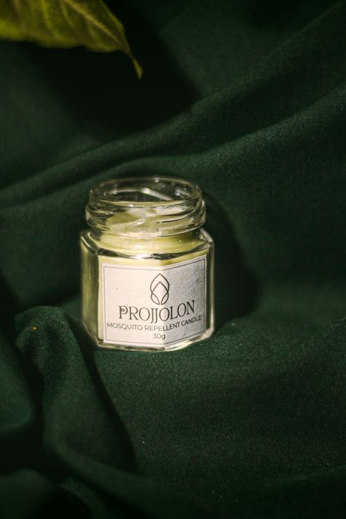 Free A natural mosquito repellent candle in a glass jar against a dark green background. Stock Photo