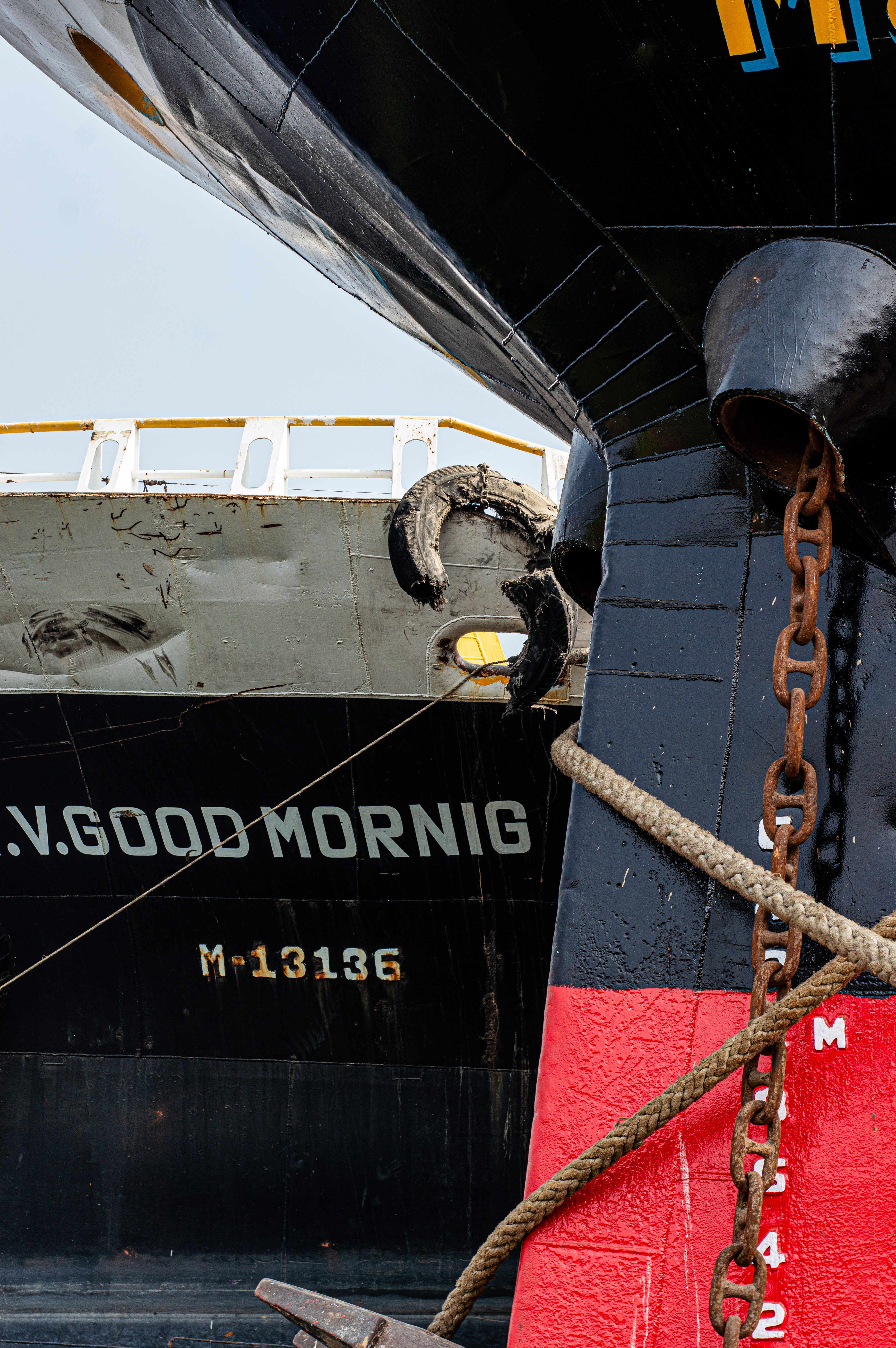 Detailed view of docked cargo ship in Dhaka port showing the ship's hull and anchoring chains.