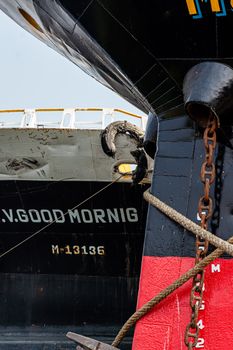 Detailed view of docked cargo ship in Dhaka port showing the ship's hull and anchoring chains.