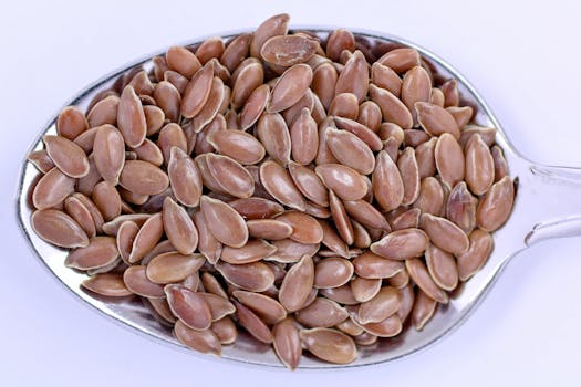High-resolution close-up of flaxseeds on a metal spoon, showcasing detail and texture.