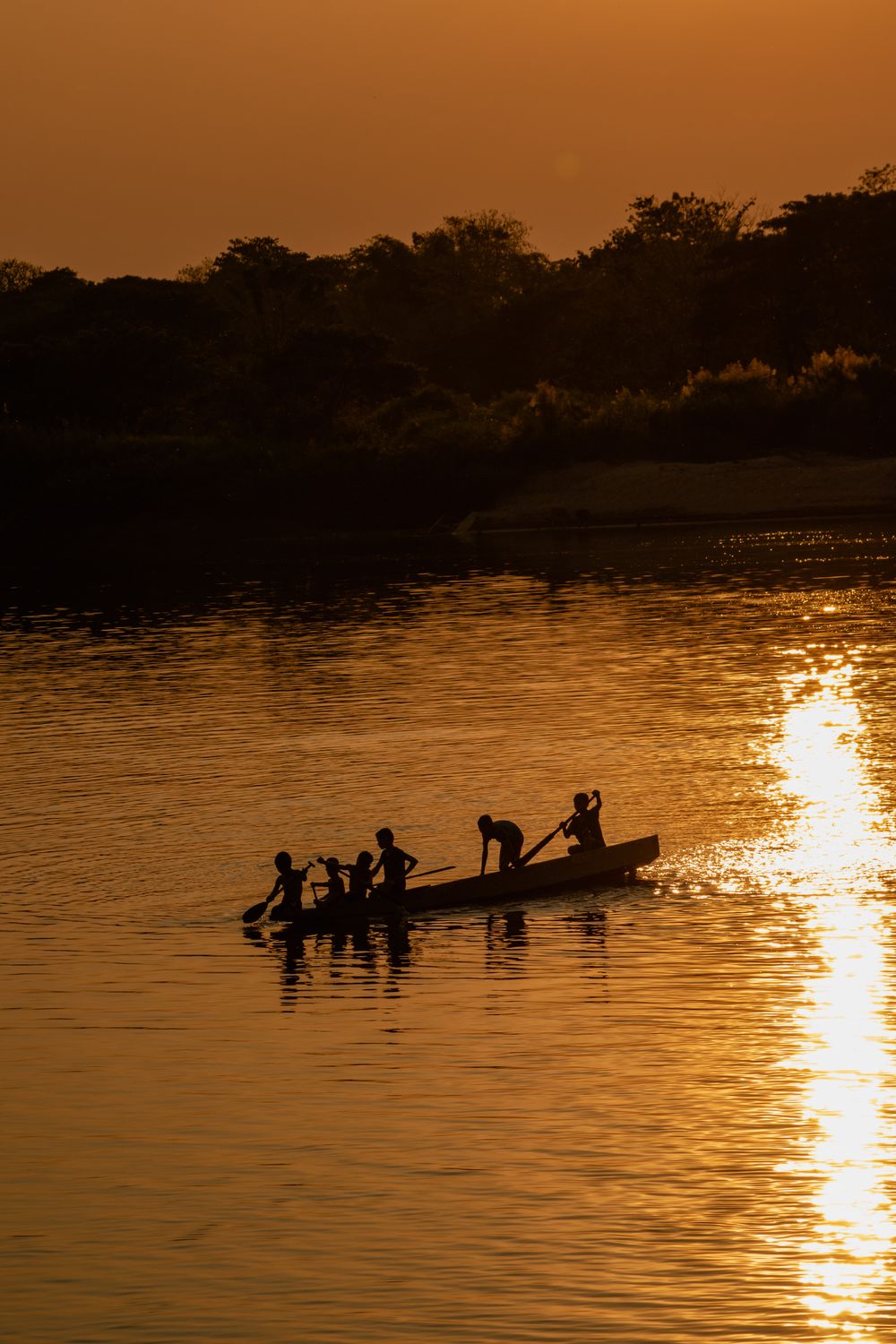 Silueta de canoa sobre el Mekong al ocaso con cielo dorado