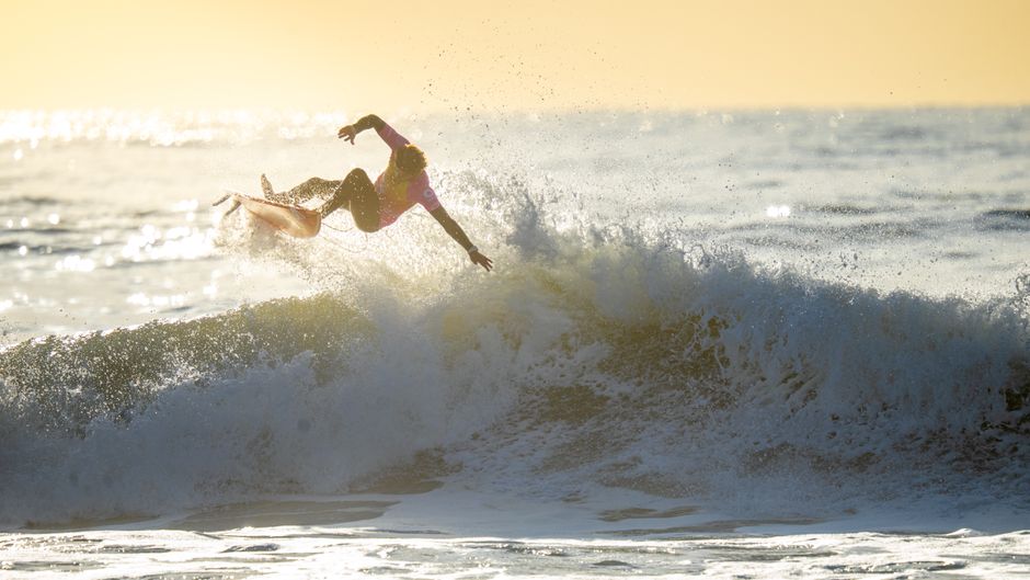 Surfer catching a wave at sunset, showcasing skill and agility.