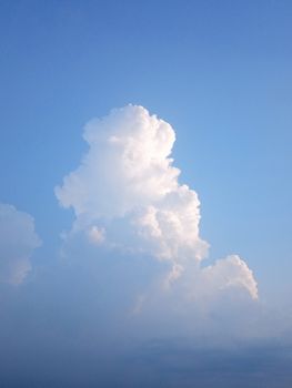 A towering cumulus cloud set against a clear blue sky, captured on a sunny day.