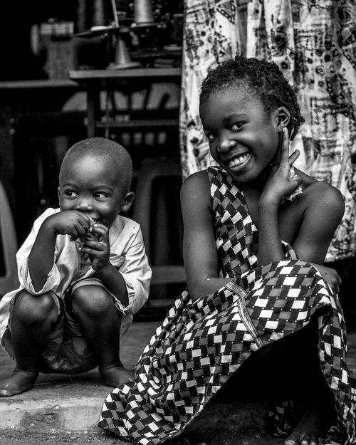 Free Two smiling African children, expressing joy and tradition in a vibrant street scene. Stock Photo