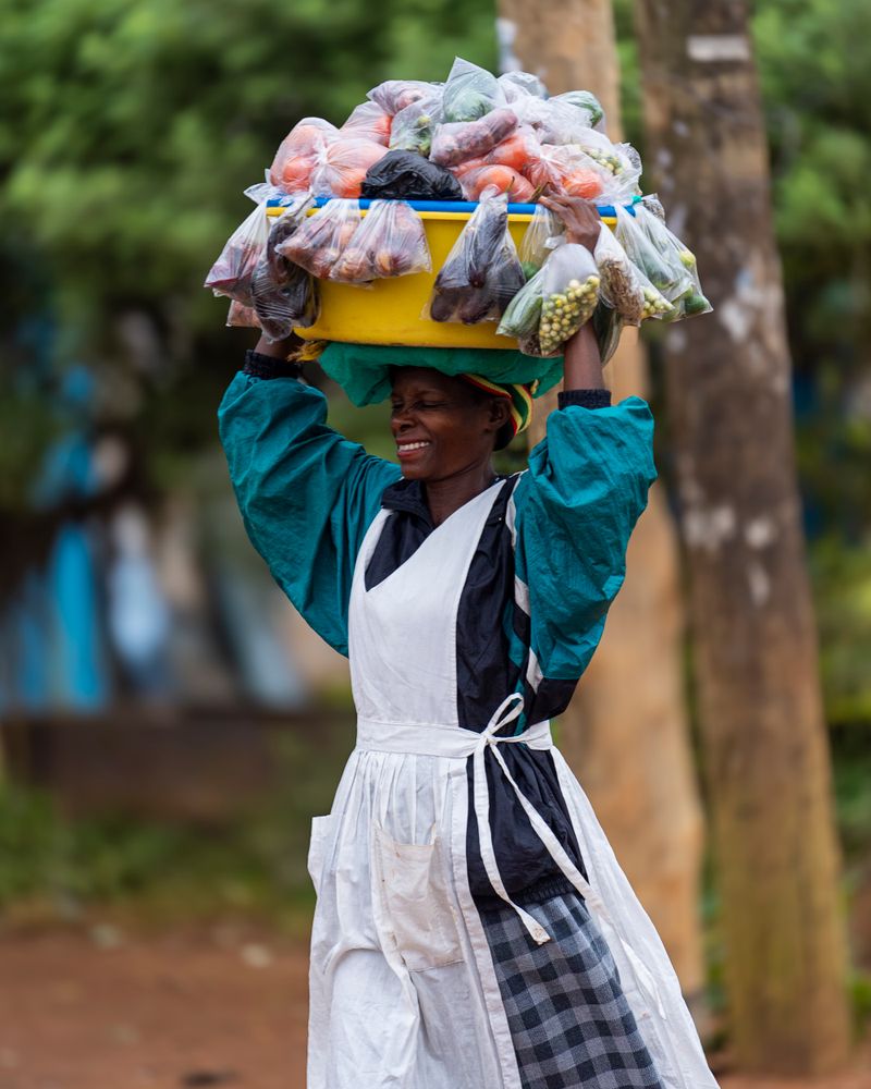 Ugandan vendor carrying fresh vegetables for her market business