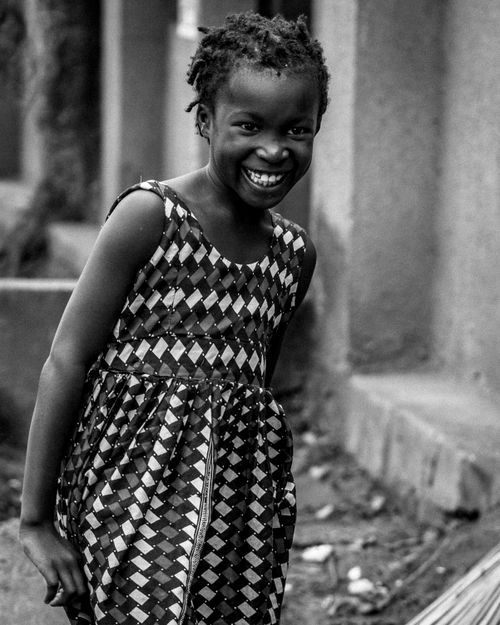 Free A joyful child smiles brightly while standing outdoors, captured in striking black and white. Stock Photo