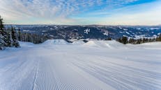在晴朗的冬季天空下，雪地滑雪坡享有令人惊叹的山景，非常适合滑雪冒险