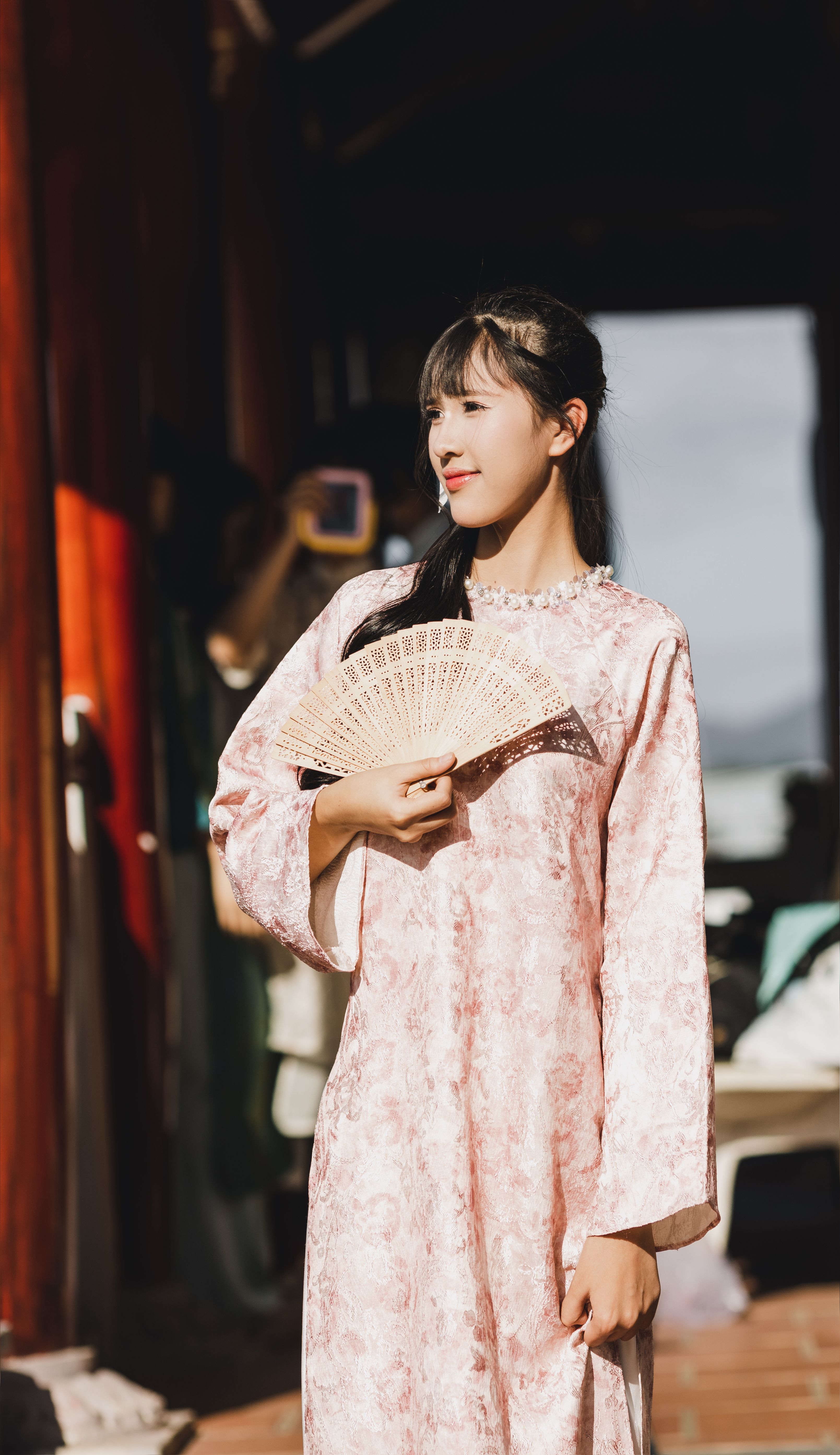 A woman in traditional Vietnamese attire holds a fan outdoors in Kon Tum.