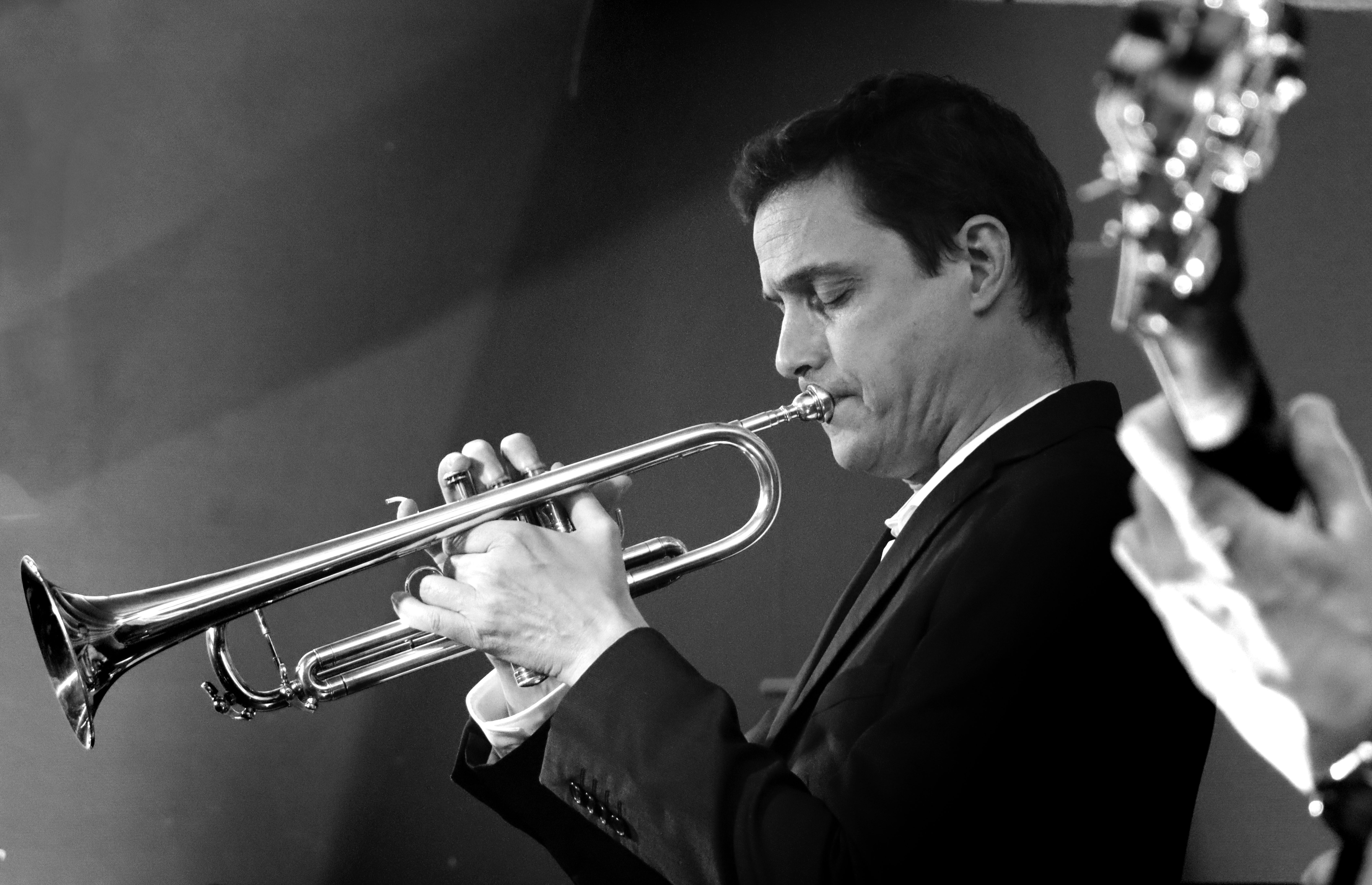 Elegant black and white photo of a trumpet player performing live at a jazz concert. Captures musical passion.