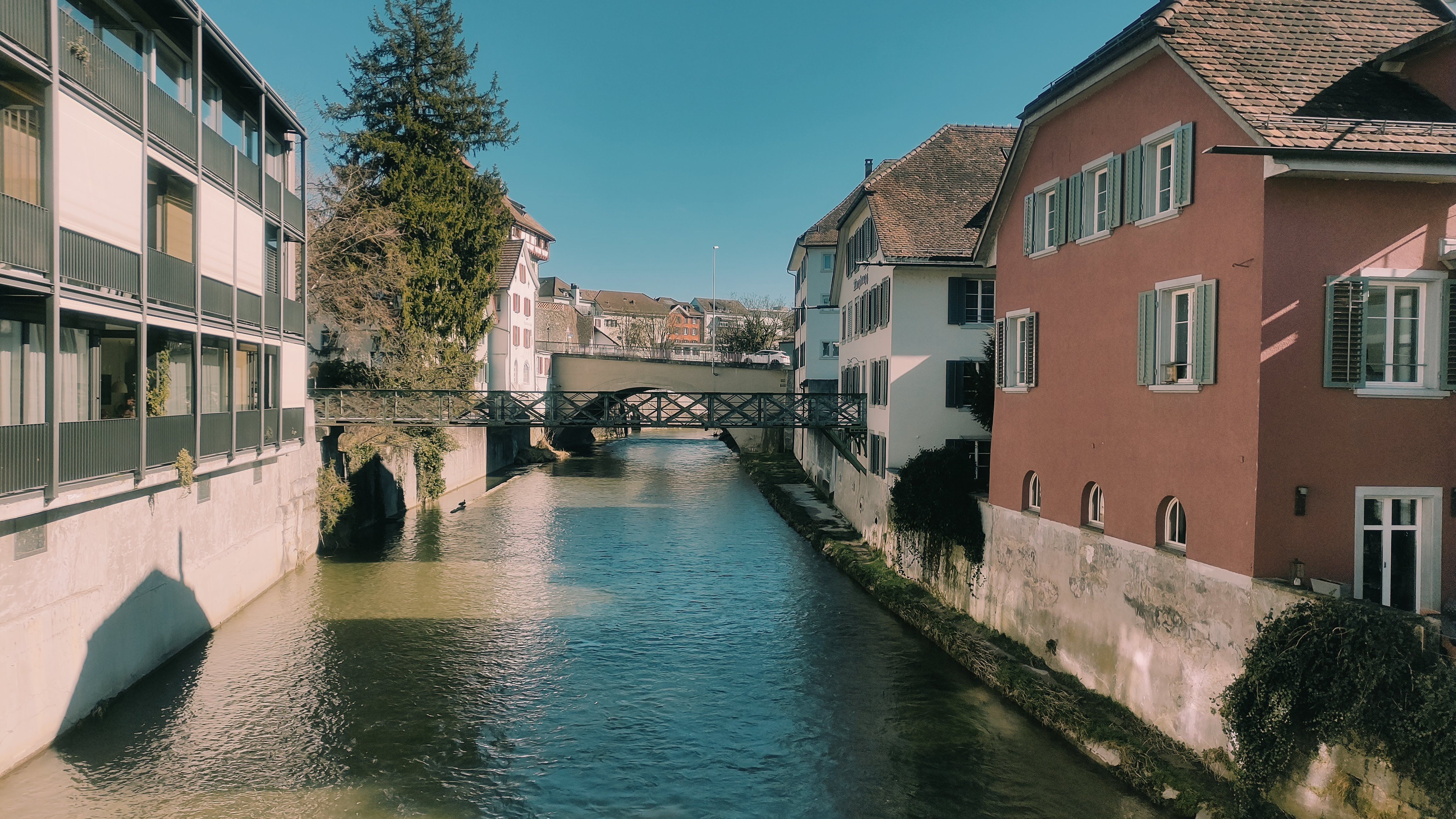 Scenic view of a river flowing through Frauenfeld, Switzerland, with historic buildings on both sides.