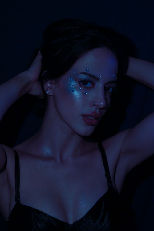 Free Mysterious woman in dark lighting with artistic blue makeup and highlights on her face. Stock Photo