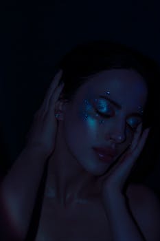 Dark, intimate portrait of a woman with glitter makeup, creating a moody and artistic feel.