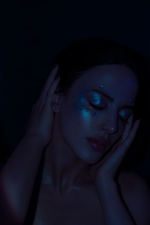 Free Dark, intimate portrait of a woman with glitter makeup, creating a moody and artistic feel. Stock Photo