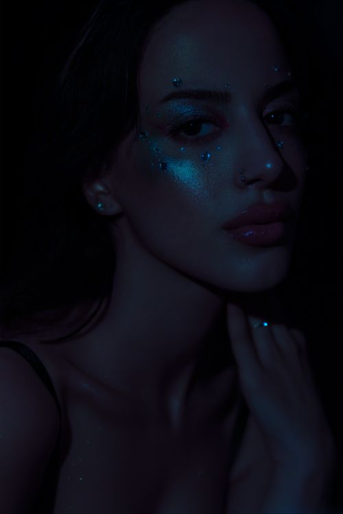 Free Artistic portrait of a woman with shimmering makeup in dim lighting. Stock Photo