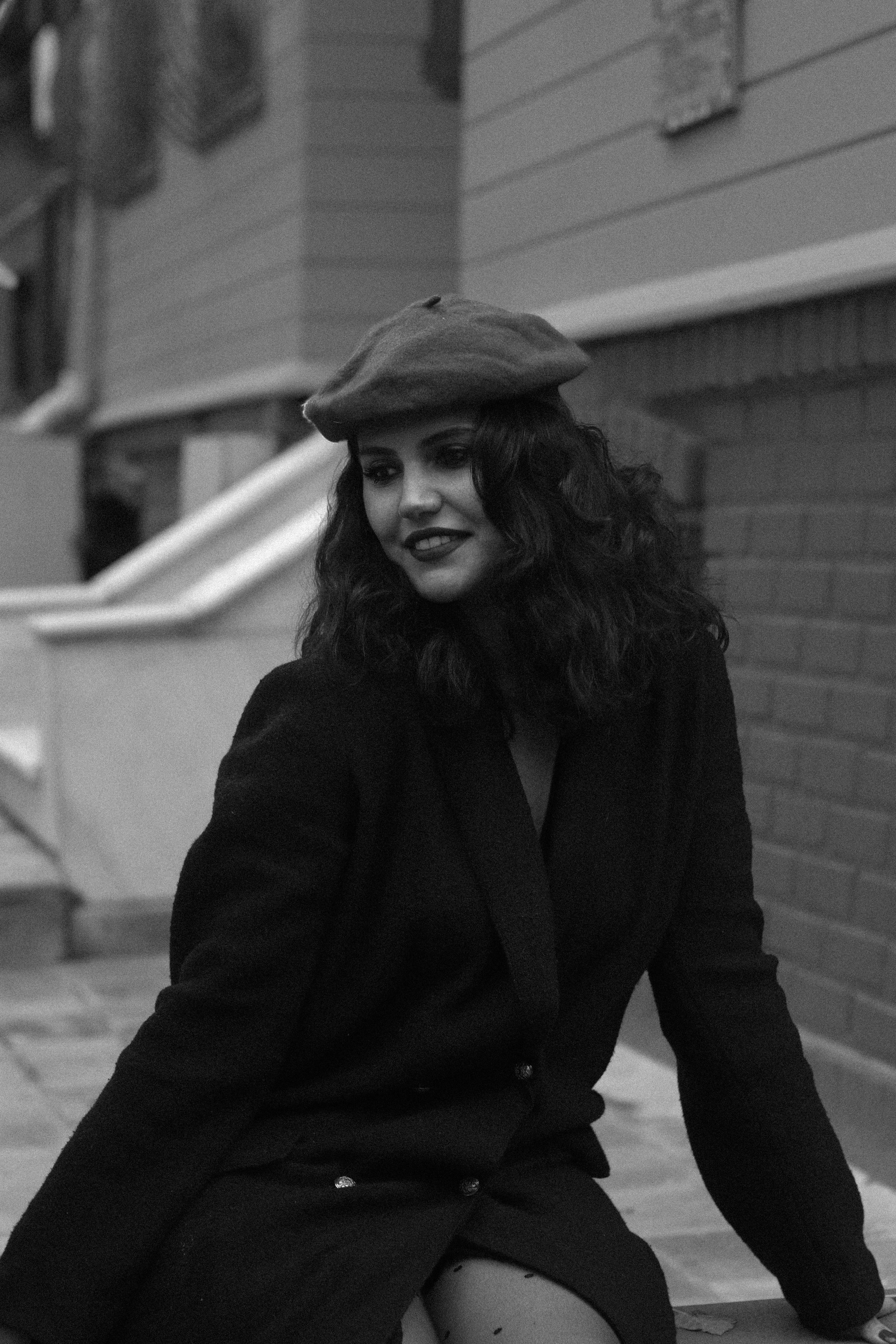 Stylish woman in a beret poses in an urban setting, exuding classic elegance.