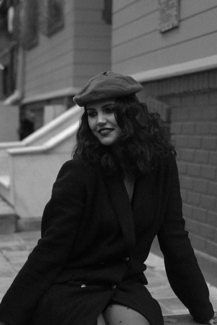 Stylish woman in a beret poses in an urban setting, exuding classic elegance.