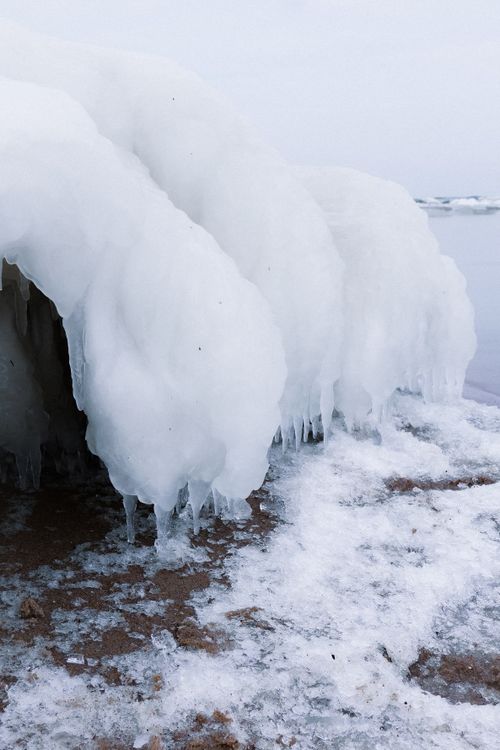 Free Stunning ice formation with icicles near a serene frozen water lake or sea. Stock Photo