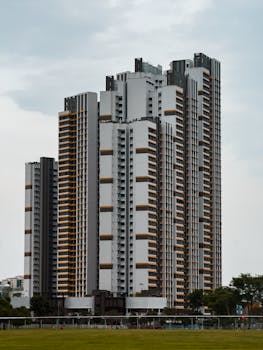 Tall modern residential skyscraper under cloudy sky, urban cityscape.