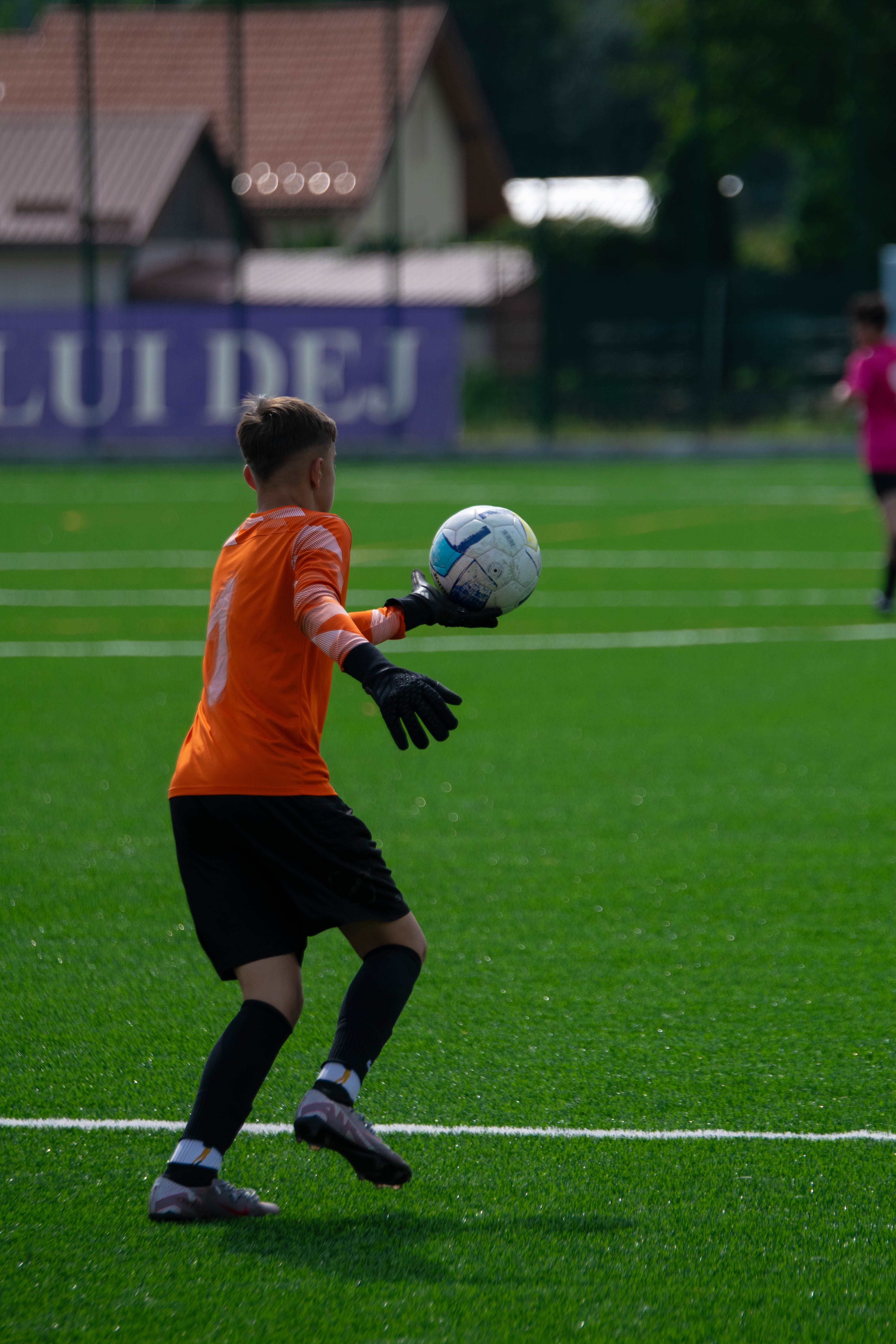 Young soccer goalie in action preparing to throw the ball during an outdoor match.