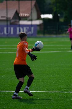 Young soccer goalie in action preparing to throw the ball during an outdoor match.