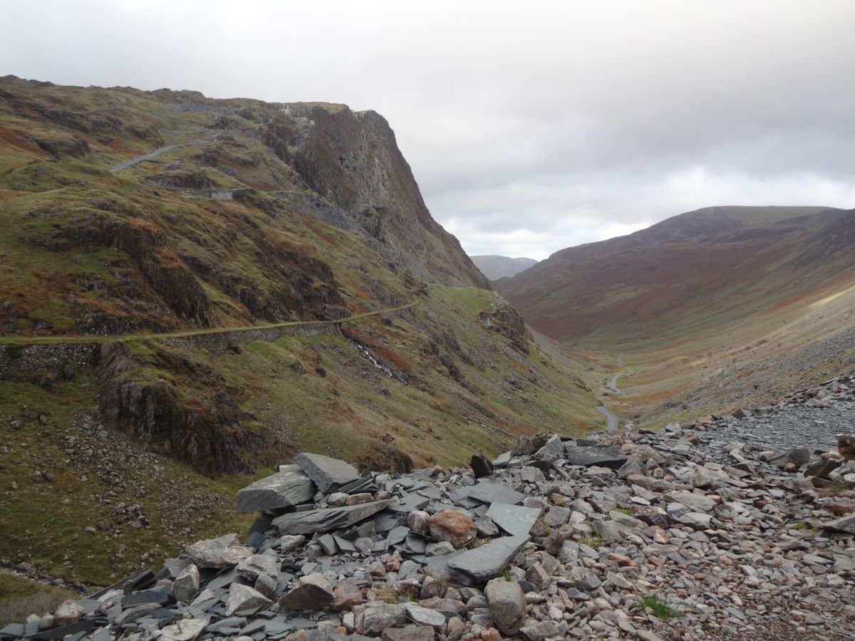 A rocky mountain pass with slate spoil and a winding track in the Lake District.