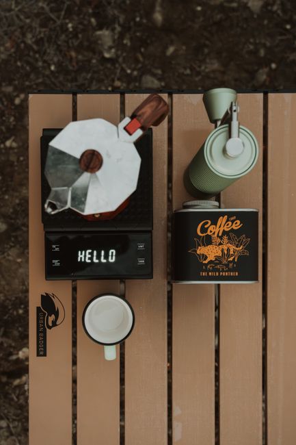 Flat lay of organized camping gear on a picnic table with labeled bins and a notebook checklist