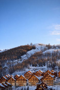 Scenic view of wooden chalets in the snowy French Alps at sunrise.