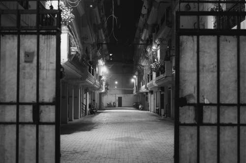 Free Moody black and white photo of a deserted urban alley at night. Stock Photo