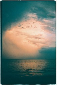 A captivating seascape during sunset, highlighting stormy clouds over the ocean.