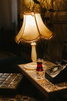 Cozy vintage setting featuring a classic lamp, rotary phone, and Turkish tea on a patterned table.