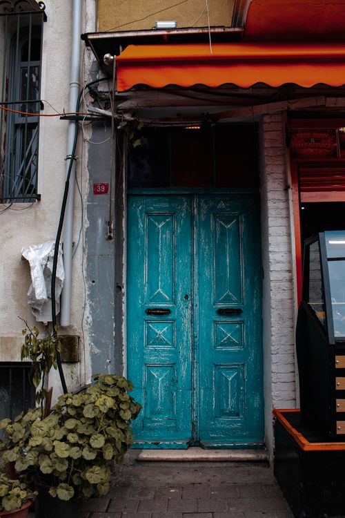 Free Photograph of a vintage teal door on a city street, featuring rustic charm. Stock Photo
