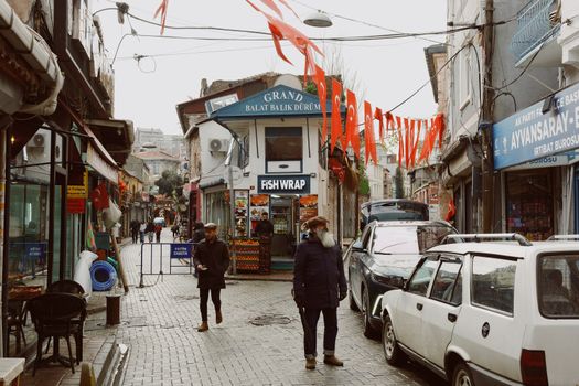 Charming street view of Balat in İstanbul featuring colorful flags and local shops.
