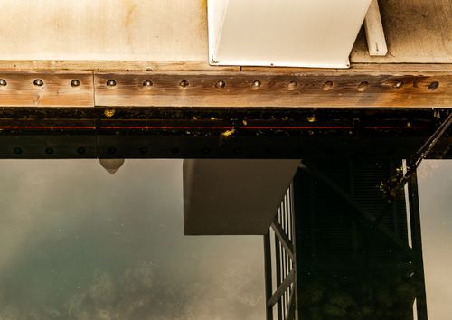 Free A moody and artistic reflection of a dock's structure on calm water, featuring industrial details. Stock Photo