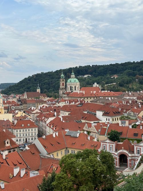 Free Aerial view of historic buildings with red rooftops in Prague, showcasing St. Nicholas Church. Stock Photo