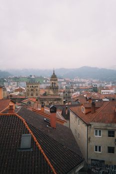 Discover the charming historic architecture of Oviedo from above with a misty backdrop.