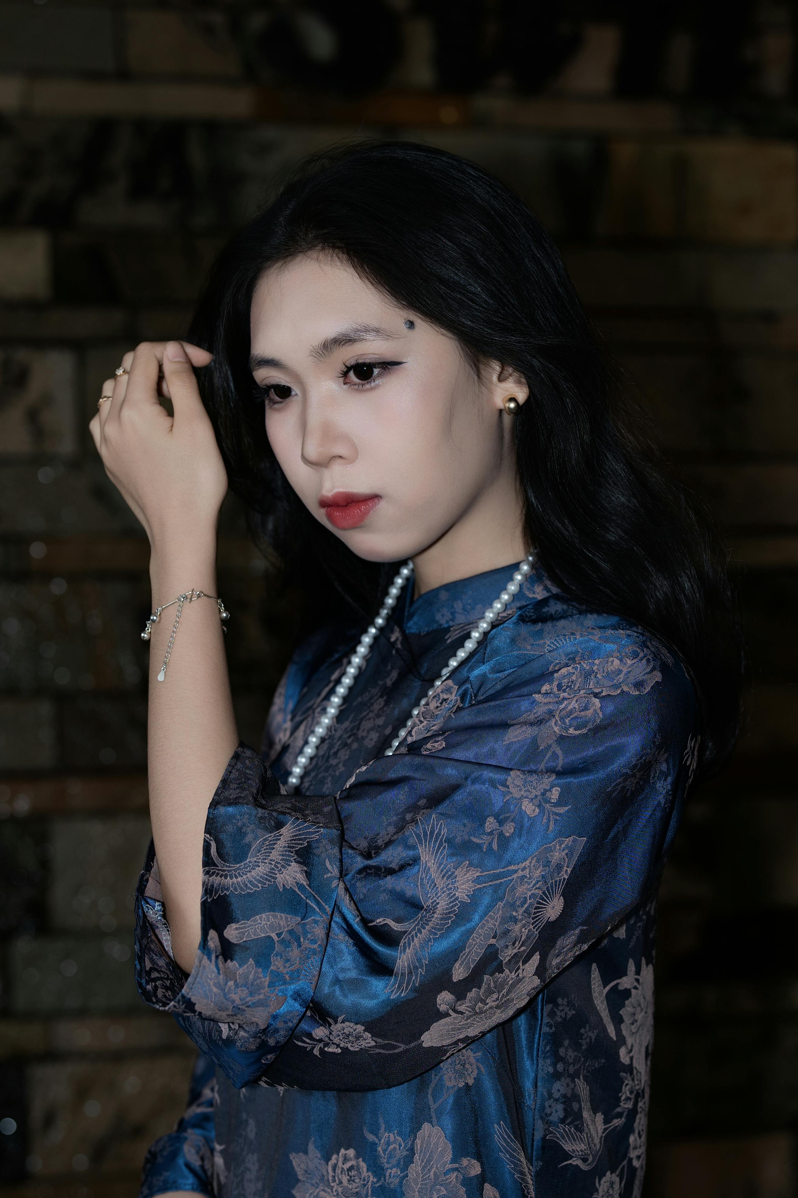 Portrait of an elegant woman in a blue silk robe with jewelry indoors. Sophisticated and serene.