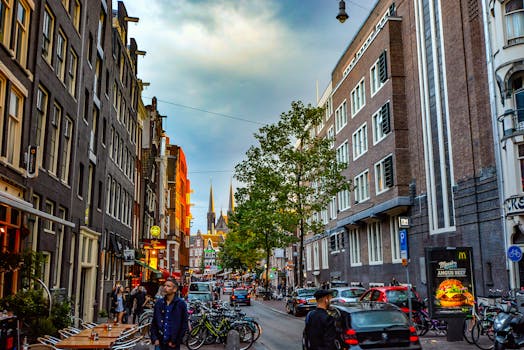 Lively Amsterdam street capturing architecture, bikes, and urban life at dusk, showcasing the city's unique charm.