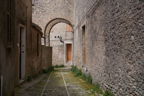Free Explore a historic cobblestone alley in Erice, Sicily, Italy, showcasing classic stone architecture under a serene sky. Stock Photo