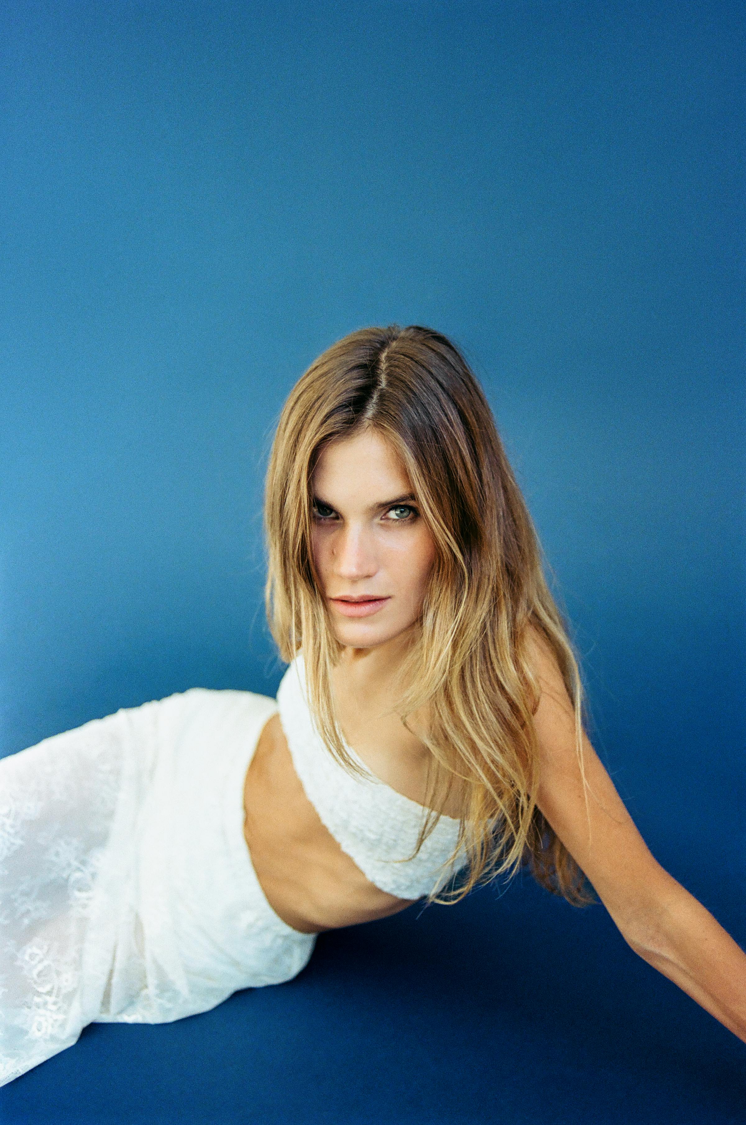 Stylish portrait of a woman in an elegant fashion pose against a blue background.