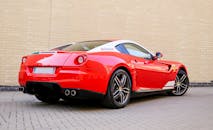 后视图中，一辆豪华的红色跑车停在砖路上，展示其圆滑的设计