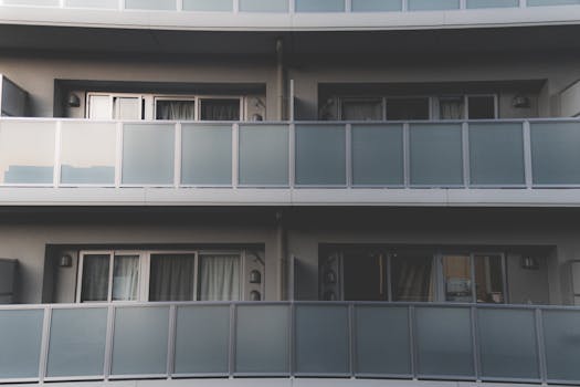 Minimalist architecture of a modern apartment building with frosted glass balconies.