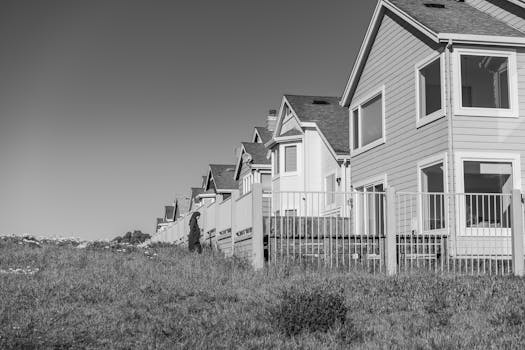 A row of suburban houses with a picket fence in black and white, capturing an outdoor serene environment.