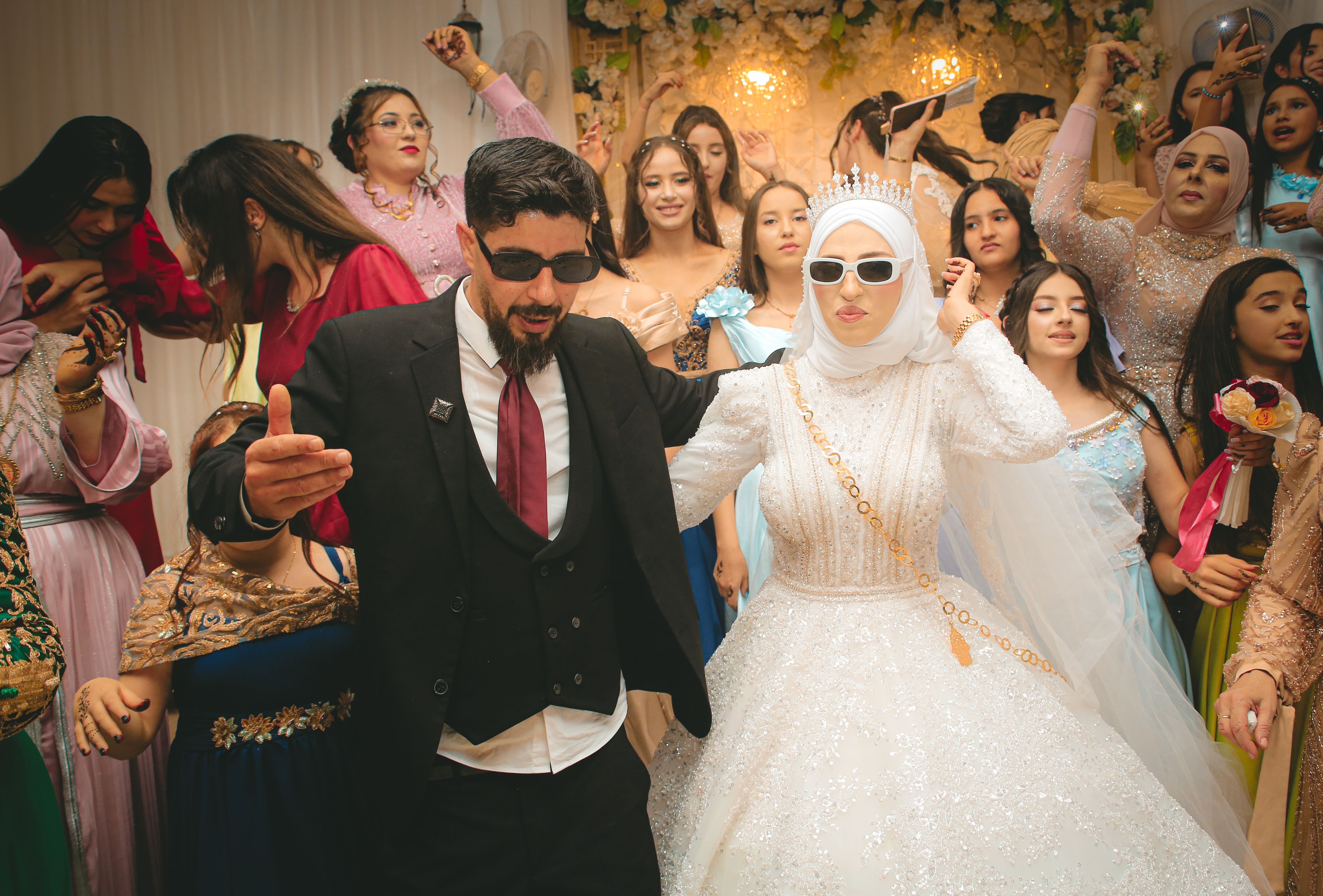 Joyful wedding celebration with stylish bride and groom dancing surrounded by guests.