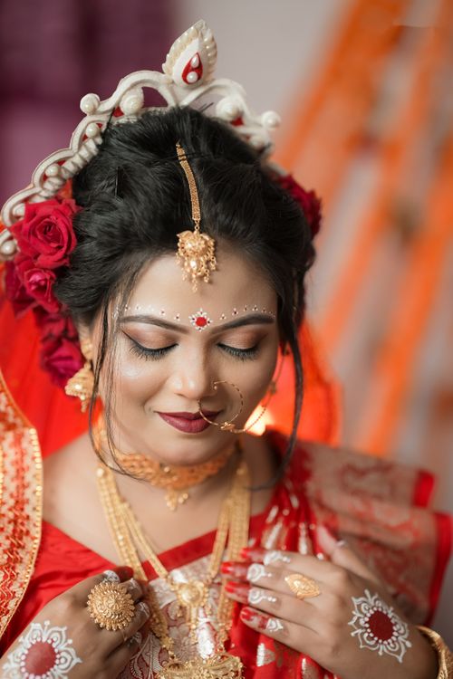 Free A beautiful South Asian bride in traditional Bengali attire adorned with gold jewelry and intricate makeup. Stock Photo