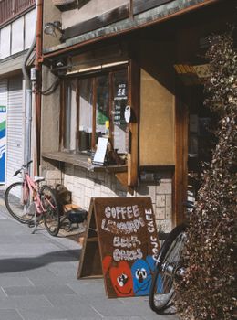Rustic cafe entrance with handwritten chalkboard, pink bicycle, cozy outdoor setting.
