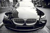 一辆闪亮的黑色豪华轿车前视图映出城市建筑，尽显优雅与风格