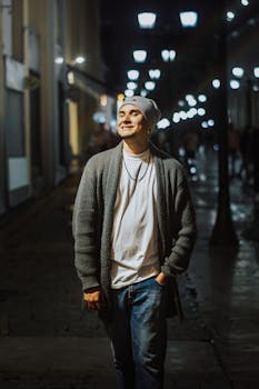 A young man walks confidently down a well-lit street at night, capturing urban nightlife vibes.