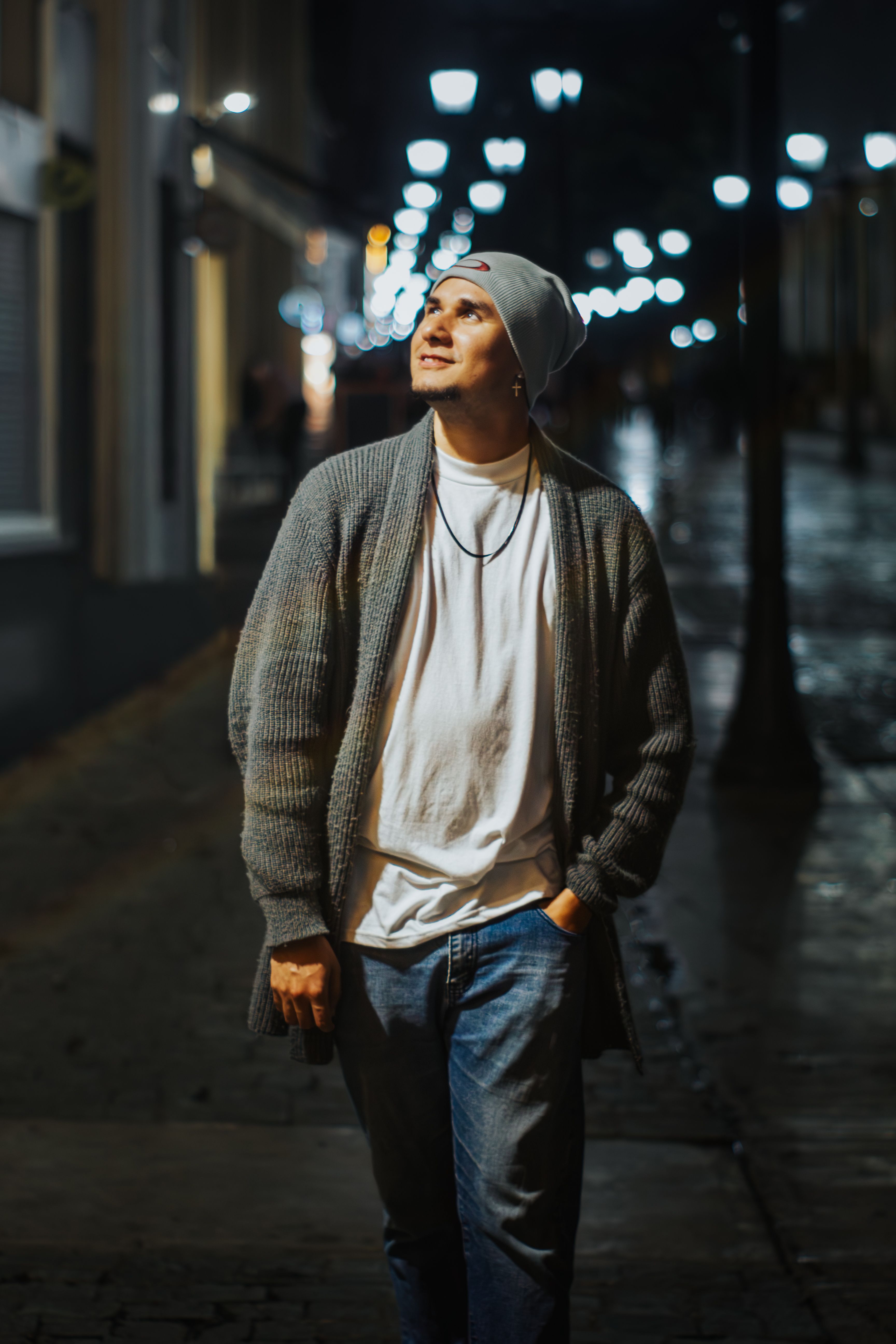 Fotomural Un joven camina por una calle de la ciudad poco iluminada, disfrutando del ambiente nocturno.
