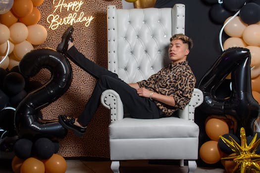 A young adult celebrates a birthday with a modern balloon setup and stylish outfit.